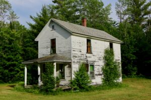white wooden house surrounded by grass and trees